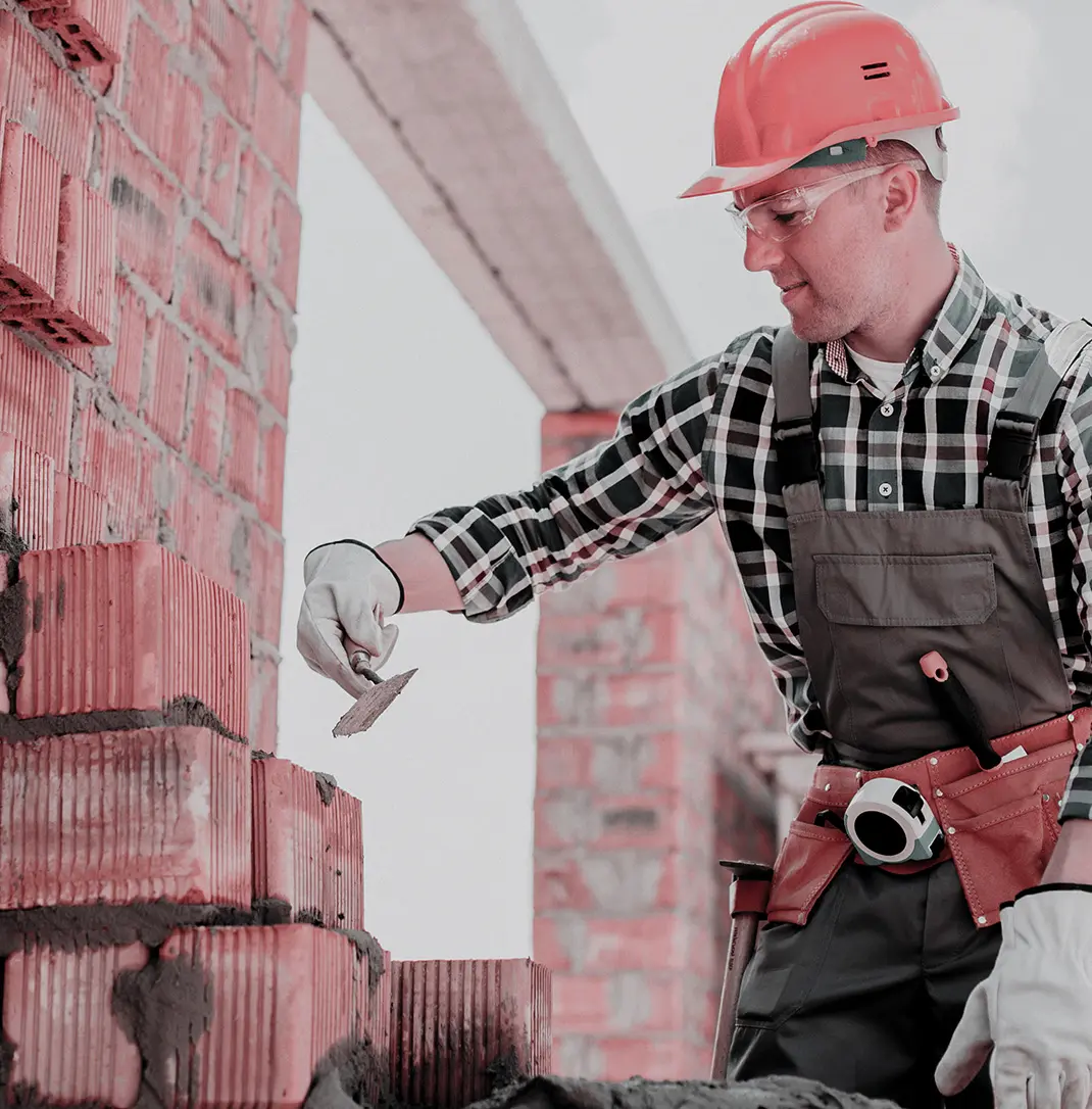Ein Handwerker zieht eine Backsteinwand mit Zement hoch